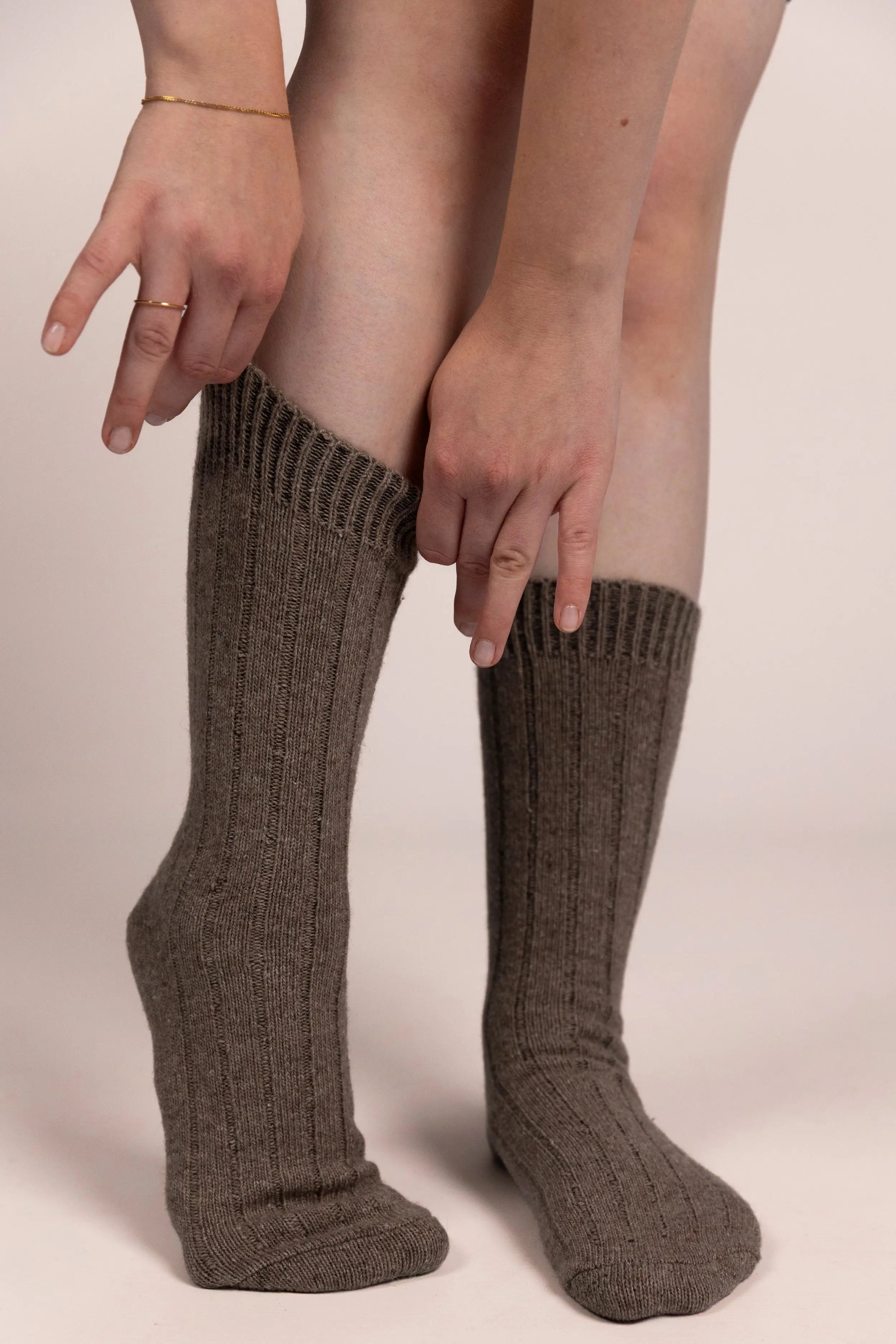 Person wearing brown cashmere socks on a plain background