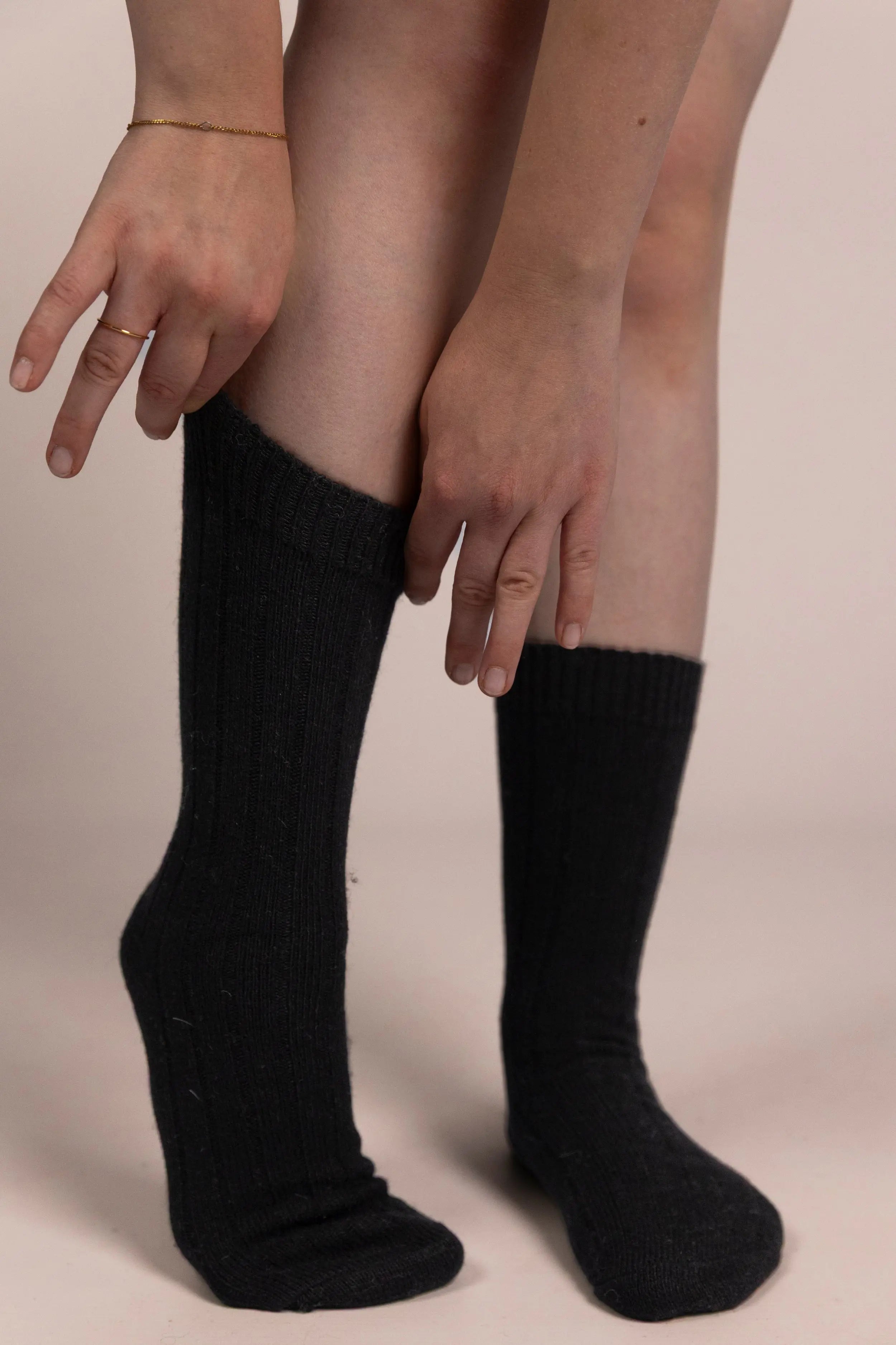 Black cashmere socks worn by a person on a neutral background