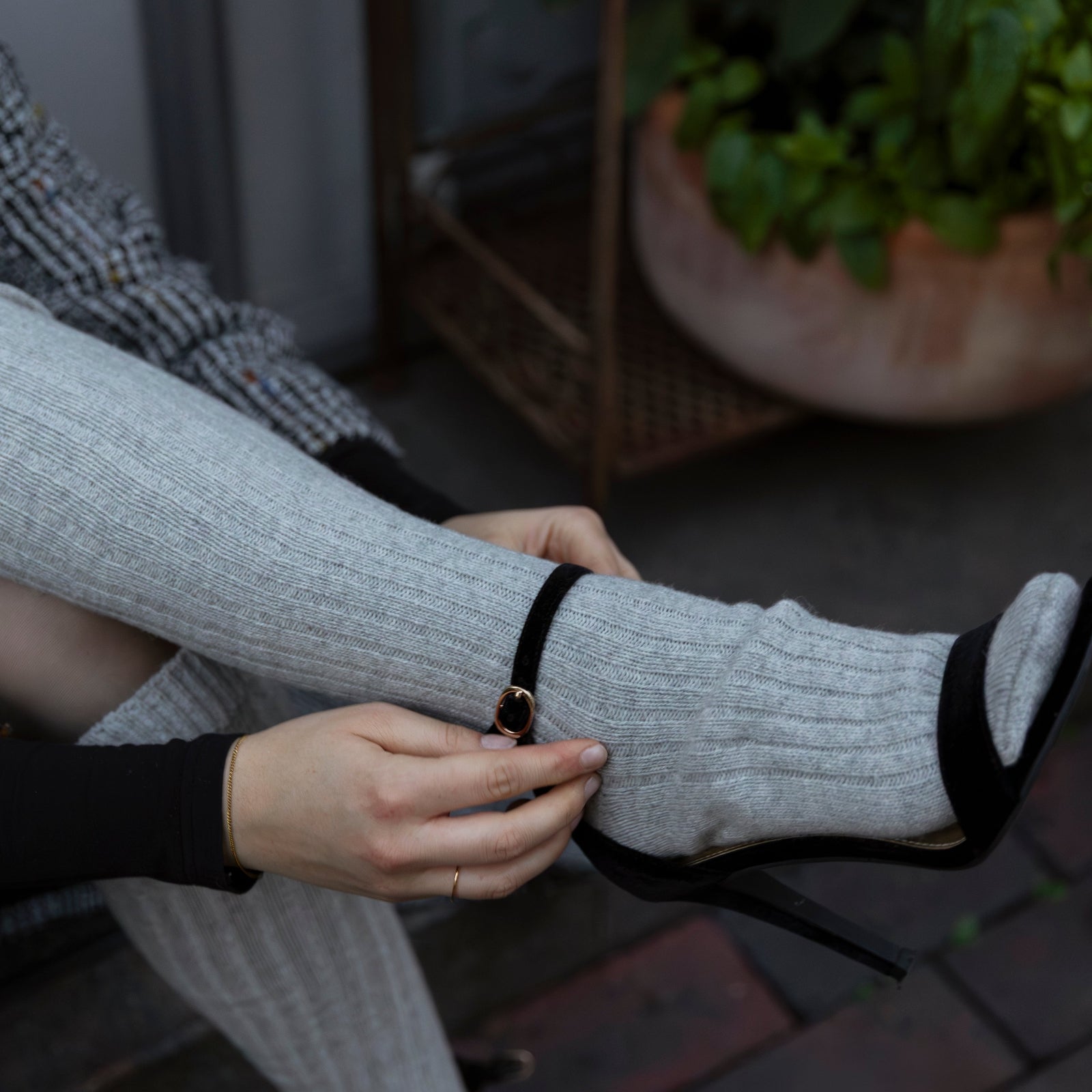 Person wearing gray socks with black accents on a wooden deck.